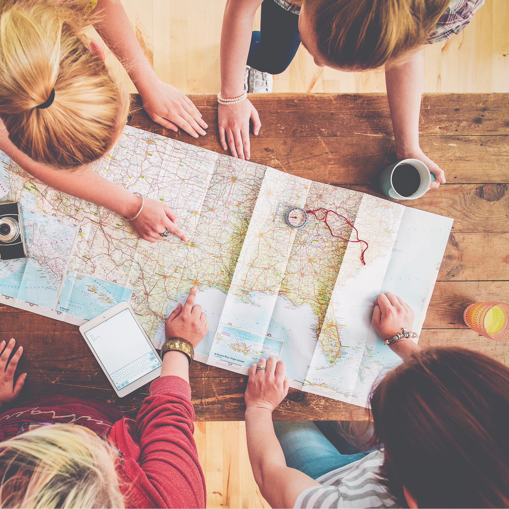 Fyra kvinnor planerar en resa med en karta på ett bord