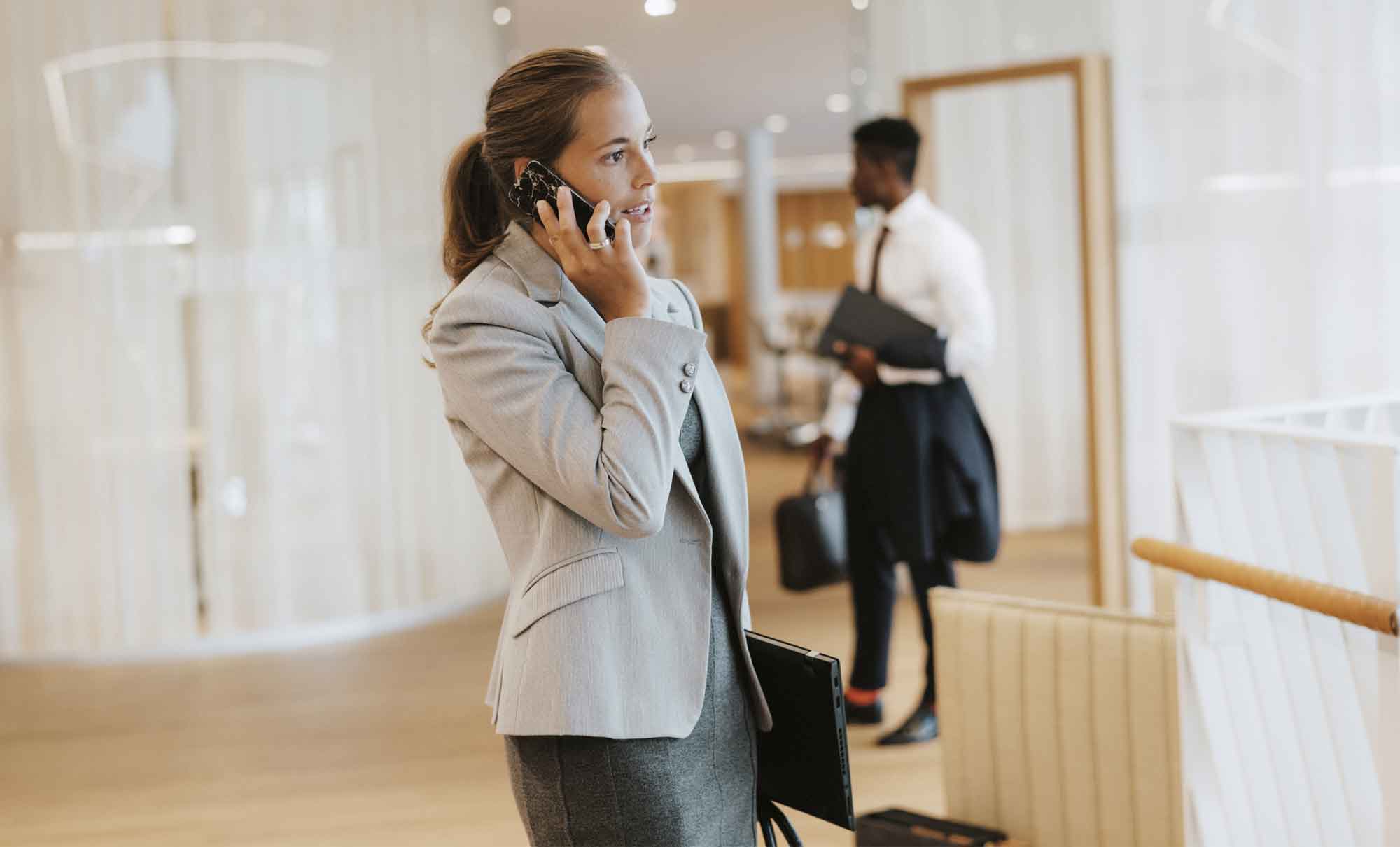 Kvinna står och pratar i telefon på kontoret